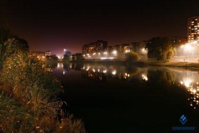 Опори вуличного освітлення в темряві біля водойми в місті 