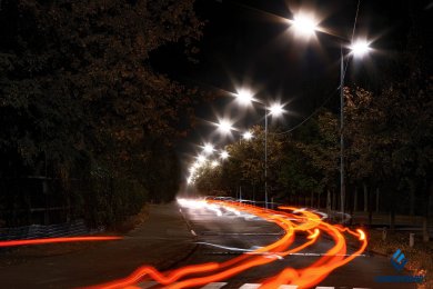 Опори вуличного освітлення в місті на фоні швидкого руху транспорту