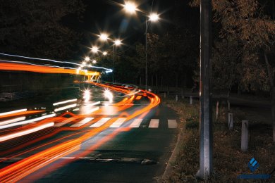 Опори вуличного освітлення біля дороги в темряві на фоні руху транспорту