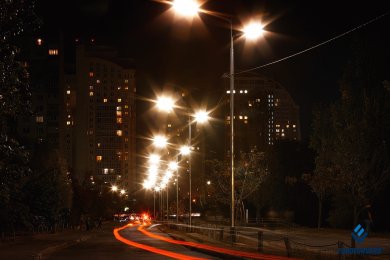Опори вуличного освітлення біля дороги в темряві на фоні руху авто