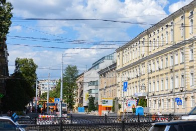 Опоры контактной сети на тротуаре возле городской дороги и зданий